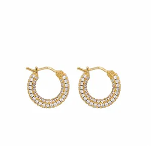 Close-up of golden hoop earrings with multiple rows of pavé set white crystals for women