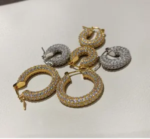 Close-up of gold and silver pavé hoop earrings with white zircon on leather background
