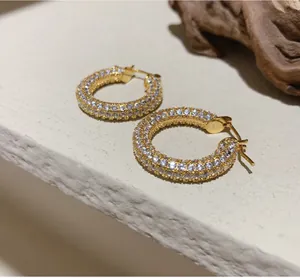 Detailed close-up of gold hoop earrings with multi-row pavé set white zircon stones