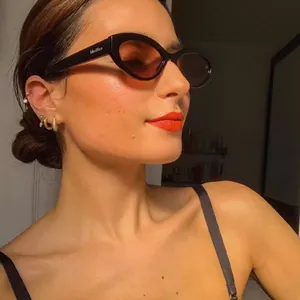 Classic black cat-eye sunglasses with dark red lenses and gold metal temple accents