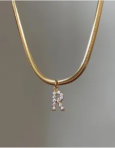 Detalle de collar de cadena de serpiente dorada con colgante letra R de micro-pavé de circón