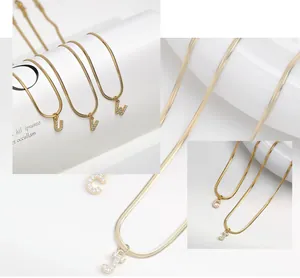 Detalle del collar de cadena de serpiente dorada con colgantes de letras con cristales