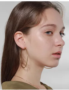 Macro shot of large polished gold hoop earrings on model for a minimalist luxury look
