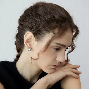 Pendientes redondos de plata S925 mate usados por una modelo sobre un fondo blanco limpio