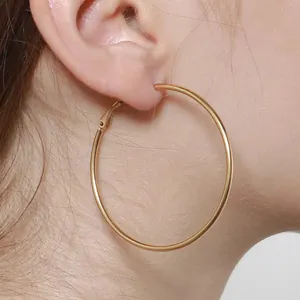Chic oversized gold hoop earrings in polished titanium steel worn for a trendy style