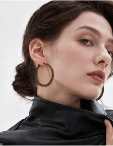 Gros plan de créoles à motif léopard portées par un mannequin en veste de cuir noir