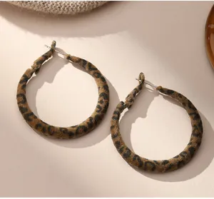 Gros plan sur des boucles d'oreilles créoles léopard en velours avec tiges en métal