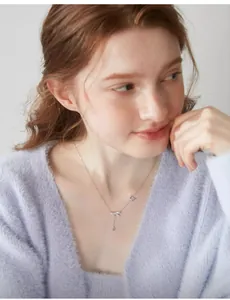 Dettaglio della collana con pendente a fiocco e nappa indossata da una modella