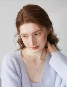 Primo piano della collana con ciondolo a fiocco d'argento indossata da una modella in maglia