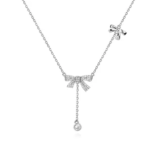 Primo piano di una collana in argento con ciondolo a fiocco e pietre luccicanti.