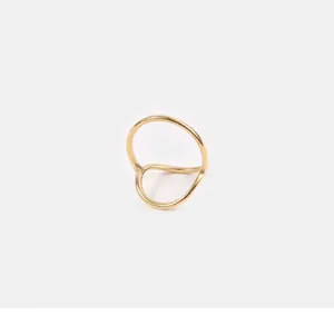 Close-up of minimalist gold hollow geometric ring with polished wavy curved design