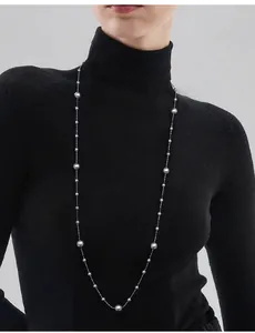 Long grey pearl sweater necklace layered over a black turtleneck for a luxurious style