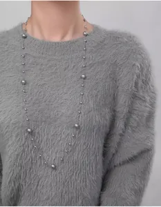 Detailed view of grey long layered pearl necklace on a grey sweater stylish outfit