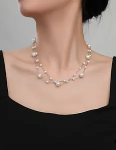 Detail of layered silver chain necklace with varying sizes of lustrous white pearls