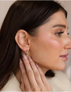 Close-up of a small gold hoop earring worn by a model, showing style and scale