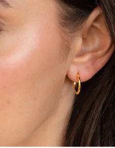 Close-up of minimalist gold hoop earrings on model for a classic everyday look