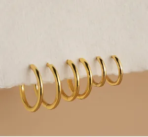 Set of six polished gold hoop earrings shown clipped on a textured white paper edge