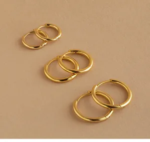 Detailed set of three gold hoop earrings in small, medium, and large sizes on textured paper