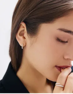 Gros plan d'un mannequin portant des créoles dorées et une bague croisée avec diamants