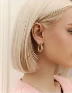 Close-up of elegant gold hoop earrings with sparkling pavé crystals worn by a model