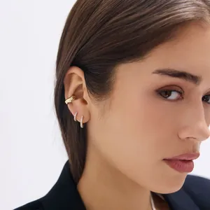Parure de boucles d'oreilles créoles dorées et ear cuff avec zircons sur un modèle