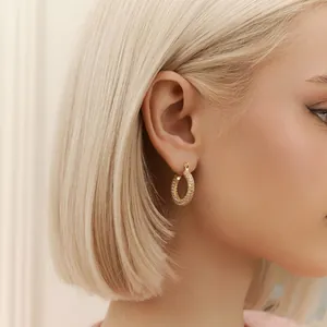 Elegant gold pave hoop earrings with sparkling cubic zirconia on female model