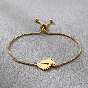 Golden baby footprint pendant bracelet with adjustable box chain on grey leather