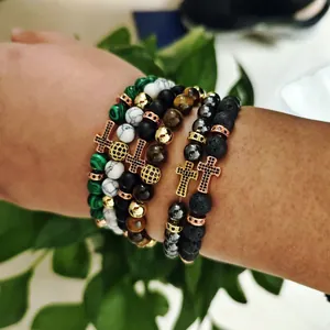 Detail of layered beaded bracelets with tiger eye stones and a copper cross charm