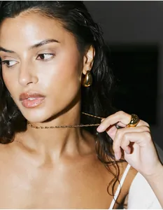 Close-up of luxury gold twisted necklace with teardrop earrings and a wide band ring