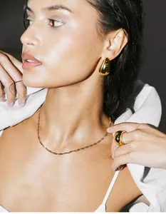 Macro shot of gold teardrop earrings and twist chain necklace on female model
