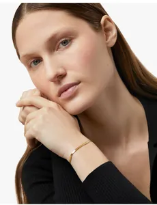 Close-up of a 18K gold herringbone snake chain bracelet on a model wrist