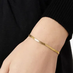 Elegant gold herringbone chain bracelet shown on model wrist with black knit sweater