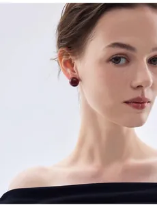 Primo piano di orecchini a bottone rossi su modella per un look festivo elegante