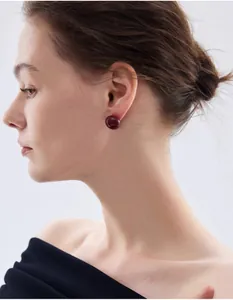 Dettaglio dell'orecchino a perla rosso bordeaux lucido indossato da una modella elegante