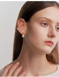 Detail van vintage gouden bol en parel oorbellen met ear cuff op model