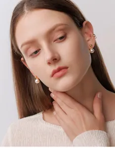 Detailopname van S925 zilveren pareloorbellen en gelaagde ear cuff gedragen door model
