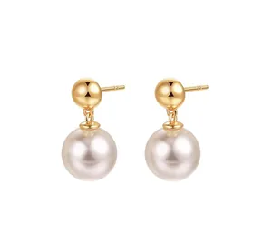 Macro-opname van gepolijste gouden bolvormige oorknopjes met elegante parelhanger