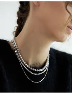 Three-layer silver layered necklace featuring ball beads and snake chains on neck