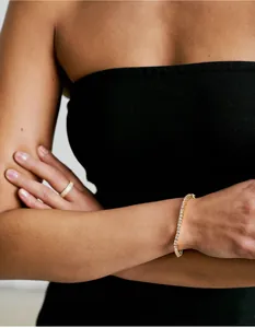 Gros plan d'un bracelet de tennis doré et d'une bague éternité diamant sur un modèle