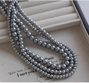 Macro detail of triple-layer grey pearl necklace on beige velvet jewelry display
