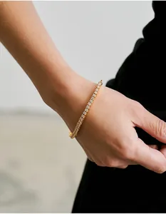 Gros plan d'un bracelet tennis doré avec des oxydes de zirconium blancs sur le poignet