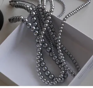 Detail view of layered grey pearls with metallic luster on a white jewelry box