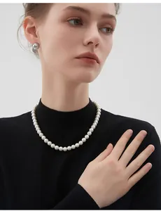 Collier élégant de perles blanches rondes sur pull noir à col roulé, style luxueux