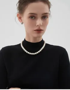 Gros plan d'un collier de perles blanches rondes sur un pull à col roulé noir