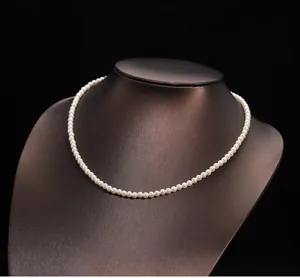 Détail d'un collier de perles blanches rondes sur mannequin brun à haute brillance