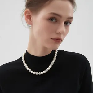 Parure élégante collier de perles blanches rondes et boucles d'oreilles sur pull noir