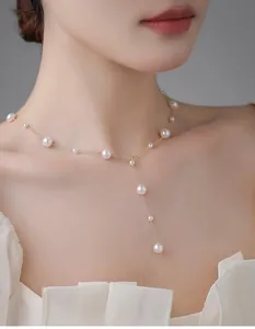 Detail of Y-shaped gold necklace featuring graduated white pearls on a female model