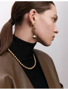 Nahaufnahme einer eleganten Goldperlenkette und langen Kettenohrringen am Modell