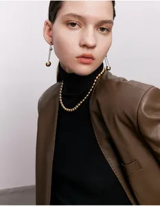 Nahaufnahme einer eleganten Perlenkette und Ohrringe an einem Model in einem Lederblazer