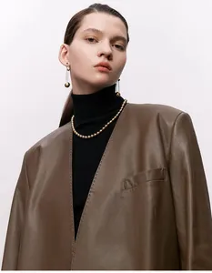 Detail einer glänzenden Perlenkette mit minimalistischen Goldperlen auf braunem Leder